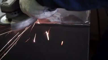 Metal parlatma disk ile bir el zımpara ile parlatma. Küçük. Fabrika işçi atölye taşlama, çelik çubuk aşındırıcı disk ve uçan ile kıvılcım. El değirmeni iş akışı oluşturma Paslanmaz boru