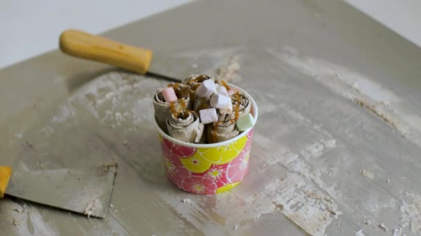 Cocinar helado de frutas naturales al estilo tailandés. Clip. Hacer rollos de helado con fruta de la pasión en el plato frío. Hacer rollos de helado en el plato frío. De cerca. Helado laminado al estilo tailandés revuelto — Vídeo de stock