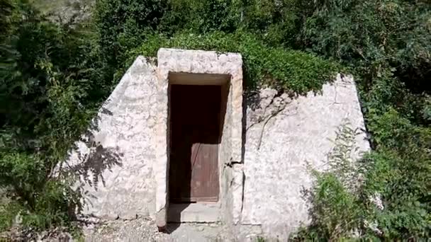 Nagyon régi bejárati kő ajtó és a fal erdőben. Szabadban épült a régi földalatti kőház alatt a zöld fűben szerkezetének. Régi kő ház mélyen az erdőben. Elhagyott kőház — Stock videók