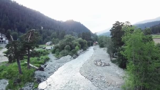 Blick von oben auf den Fluss in einer kleinen Siedlung. Berglandschaft kleine Häuser im Dorf schöne Natur und Vegetation — Stockvideo