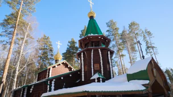 Красиві пейзажі з церквою в зимовому лісі в оточенні заморожених і покритий снігом дерева в морозний сонячний день в Росії. Храм у лісовій взимку на сонячний день — стокове відео