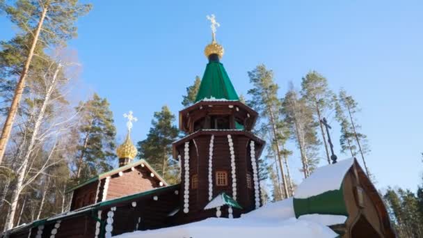 Hermoso paisaje con iglesia en un bosque de invierno rodeado de árboles de nieve congelados y cubiertos en un día soleado y helado en Rusia. Templo en el bosque en invierno en un día soleado — Vídeos de Stock