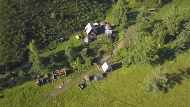 Αεροφωτογραφία του ένα μικρό χωριό στα βουνά, δάσος φόντο. Όμορφα βουνά τοπίο με ένα χωριό, το top view. Κλιπ. — Αρχείο Βίντεο