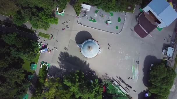 Top luchtfoto van pretpark voor kinderen op een zomerdag. Reuzenrad in het central park van de stad. Luchtfoto. Clip. — Stockvideo