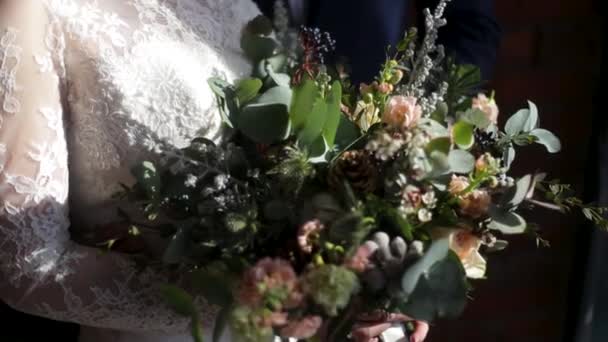 Belo buquê de noiva em mãos de jovem noiva vestida com vestido de noiva branco. Mão de noiva tocando o buquê de casamento. Close up de grande grupo de rosas brancas frescas e flores de tulipas em mãos femininas — Vídeo de Stock