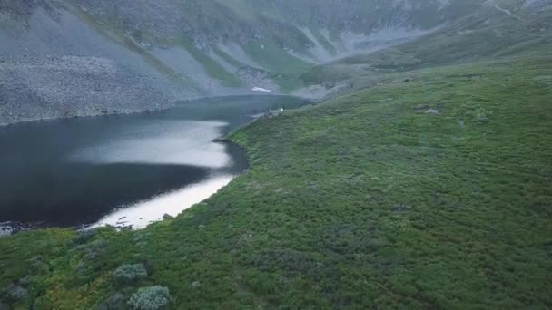 Beautiful huge green mountains peaks. Clip. Lake at the foot of the mountain. Green valley background. Top view of the green mountains with a lake at the foot — Stock Video