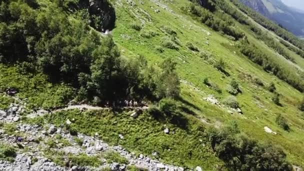 Disparos aéreos desde el grupo de senderismo de drones voladores caminando por senderos de montaña. Grupo turístico que viaja en valle de montaña. Tour de senderismo en montaña. Grupo viajero caminando por el sendero de montaña vista aérea — Vídeo de stock