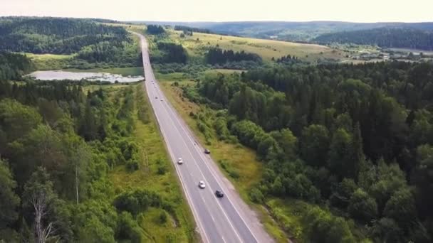 Top luchtfoto van zomer groene bomen, rivier, wegen in bos achtergrond. Luchtfoto van krom pad van weg op de berg. Clip. Luchtfoto van auto's rijden op de landweg in bos. De antenne — Stockvideo