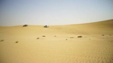 Havadan görünümü ile Dubai şehir silüetinin ya da cityscape gün batımında Arap Çölü'nde Suv ile Off-road maceraya. Çöl SUV ile turne. Offroad Suv çölde at binme. 4 çekişli Suv üzerinde sürüş