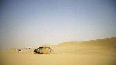 Havadan görünümü ile Dubai şehir silüetinin ya da cityscape gün batımında Arap Çölü'nde Suv ile Off-road maceraya. Çöl SUV ile turne. Offroad Suv çölde at binme. 4 çekişli Suv üzerinde sürüş