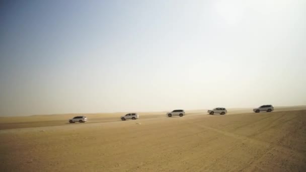 Vista aérea de la aventura todoterreno con SUV en el desierto árabe al atardecer con horizonte de Dubái o paisaje urbano. Desierto de gira con SUV. todoterreno SUV a caballo en el desierto. Conducción de un SUV de tracción en las 4 ruedas — Vídeo de stock