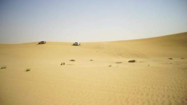 Aerial view on Off-road adventure with SUV in Arabian Desert at sunset with Dubai skyline or cityscape. Desert touring with SUV. Offroad SUV riding in the desert. Driving a 4-wheel drive SUV on the — Stock Video
