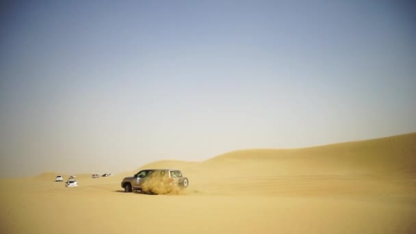 Vista aérea de la aventura todoterreno con SUV en el desierto árabe al atardecer con horizonte de Dubái o paisaje urbano. Desierto de gira con SUV. todoterreno SUV a caballo en el desierto. Conducción de un SUV de tracción en las 4 ruedas — Vídeo de stock