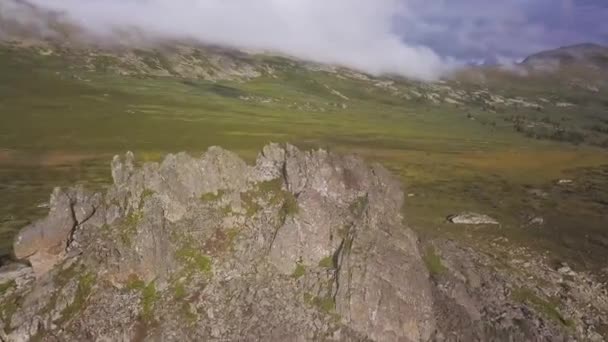 Luftaufnahme auf einer grünen Wiese mit einsamen Felsen und bewölktem Himmel. atemberaubende Berglandschaft mit großen Felsen mitten im Gras. Luftaufnahme der Bergseite — Stockvideo