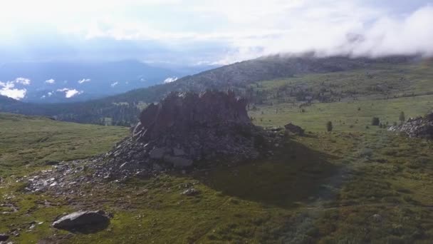 Dramatický pohled na osamělé skály v mountain meadows s pozadím světla slunce. Letecký pohled na obrovské skále na vrcholu hory s pozadím nádherné přírody. Osamělé horské stezky na hřebenu — Stock video