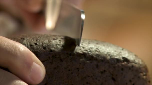 Vollkornbrot auf einem Holzteller mit einem Koch, der ein goldenes Messer zum Schneiden hält. frisches Brot auf dem Tisch in Großaufnahme. Frisches, knuspriges Brot aus nächster Nähe schneiden. Bäcker schneidet Kleiebrot — Stockvideo