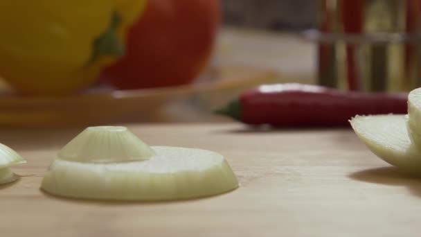 Vallende ring gesneden uien op houten snijplank. Close-up van dalende cirkels van groene ui op glazen kom van snijplank, slow-motion. Gesneden prei vallen op houten bureau voor het snijden van voedsel — Stockvideo