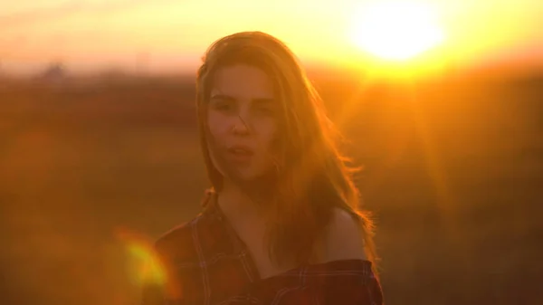 Nahaufnahme Porträt einer attraktiven jungen Frau, die im Freien lächelt. Frau bei Sonnenuntergang im Hintergrund des Steppenfeldes bei windigem Wetter. Porträt einer attraktiven Frau in der Natur bei Sonnenuntergang — Stockfoto