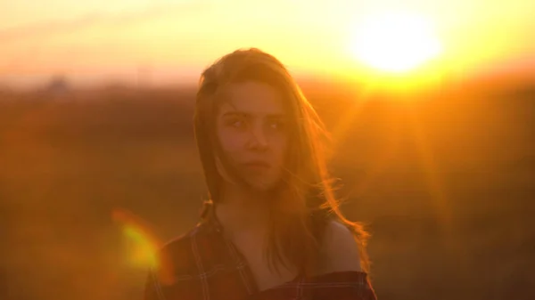 Close up retrato de uma jovem mulher atraente sorrindo ao ar livre. Mulher no pôr-do-sol fundo do campo de estepe em tempo ventoso. Retrato de uma mulher atraente na natureza ao pôr do sol — Fotografia de Stock