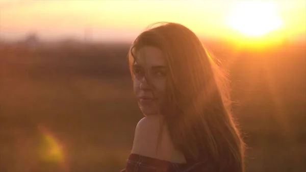 Porträt einer schönen langhaarigen Frau vor dem Hintergrund der Sonnenuntergänge. Charmante Frau mit im Wind flatternden Haaren im Sonnenuntergang — Stockfoto