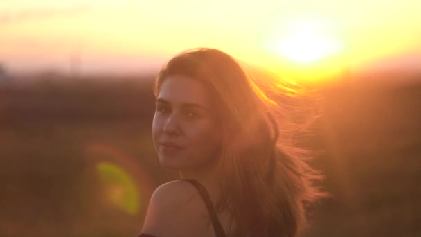 La mujer disfruta del cálido atardecer de verano. Hermosa mujer en el fondo de los rayos de sol puesta del sol — Vídeos de Stock