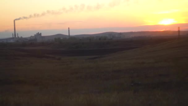 Paesaggio con impresa industriale all'orizzonte. Veduta dell'impianto industriale nei campi di steppa al tramonto. Concetto di industria moderna nell'ambiente naturale — Video Stock