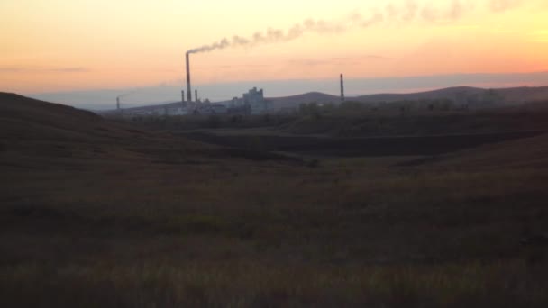 Paisaje con empresa industrial en el horizonte. Vista de la planta industrial en campos de estepa al atardecer. Concepto de industria moderna en el entorno natural — Vídeos de Stock