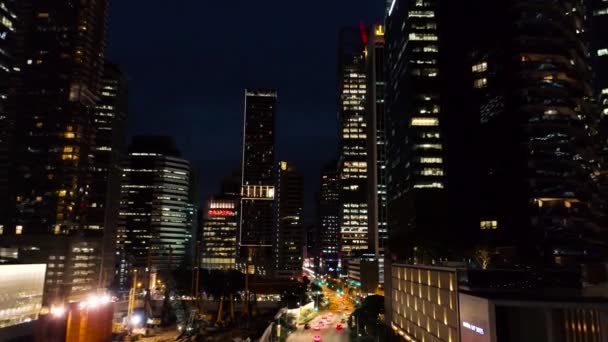 Сингапур - август 2018 года: Ночь с красивым городом в огнях рядом с ним оживленное шоссе. Выстрел. Вид сверху между небоскребами компании с освещенными окнами в ночное время. Концепция ночной жизни в — стоковое видео