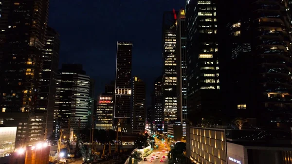 Exterior pitoresco arranha-céus modernos com janelas brilhantes de escritórios à noite. Atingido. O conceito de vida noturna em metrópole. Vista superior de escritórios de construção de arranha-céus à noite — Fotografia de Stock