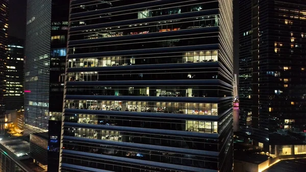 Esterno di grattacieli moderni con finestre luminose di uffici di megapolise in sera. Gli hanno sparato. Concetto di vita nella grande città. Vista dall'alto di uffici di grattacieli nel centro della città di notte — Foto Stock