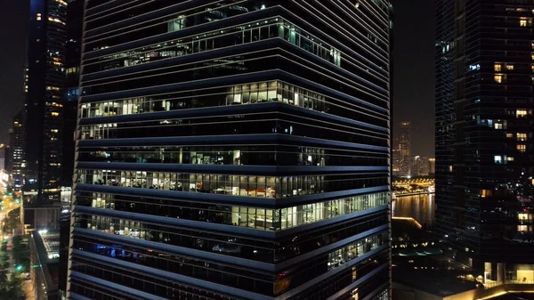 Exterior de rascacielos modernos con ventanas luminosas de oficinas de megapolise por la noche. Le dispararon. Concepto de vida en la gran ciudad. Vista superior de las oficinas del edificio de gran altura en el centro de la ciudad por la noche — Foto de Stock