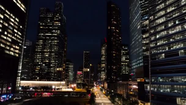 Singapur - agosto, 2018: Noche con hermosa ciudad en luces al lado de ella es la autopista ocupada. Le dispararon. Vista superior entre rascacielos de empresa con ventanas iluminadas en la noche. Concepto de vida nocturna en — Vídeo de stock