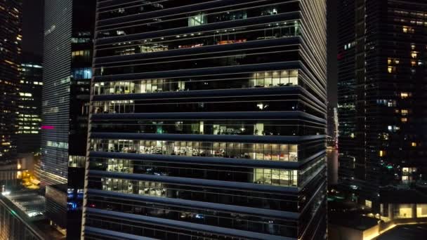 Zewnętrzny malowniczej nowoczesne wieżowce z świecące windows biura w godzinach wieczornych. Strzał. Koncepcja nocne życie w metropolii. Widok z góry z biura wieżowiec budynk w nocy — Wideo stockowe