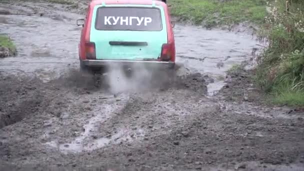 Moscow, Russia - September 2018: SUV rides through muddy puddle on off-road track, with big splash, during jeep competitions. Clip. SUV rides on mud on road. Extreme entertainment and driving concept — Stock Video