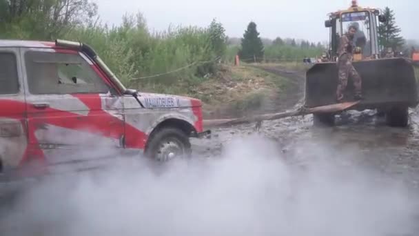 Vuile offroad auto vast in vuil op bewolkte herfstdag op weg van het platteland. Clip. SUV gesleept van plas modder — Stockvideo