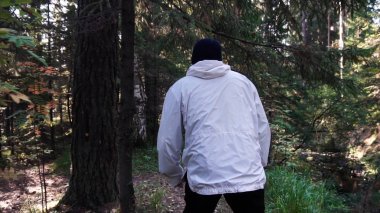 Genç adam kamp gezisinde. Özgürlük ve doğa kavramı. Adam ormanda yol boyunca güneşli sonbahar gününde yürüyüş arkadan görünümü