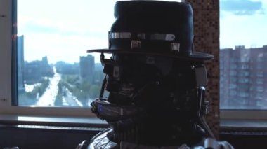 Metal android yüksek binalar şehrin görünümünü arka plan üzerinde şarap Restoran masada oturuyor. Robot adam insan gibi davranır. Teknoloji kavramı