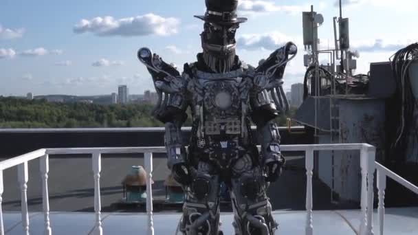 Człowieka robot w wszystkich wzrostu jest napędzany przez kończyny na tle niebieskiego nieba z chmury. Materiał filmowy. Android z twarzy i kapelusz pokazuje jego zdolność do poruszania się — Wideo stockowe