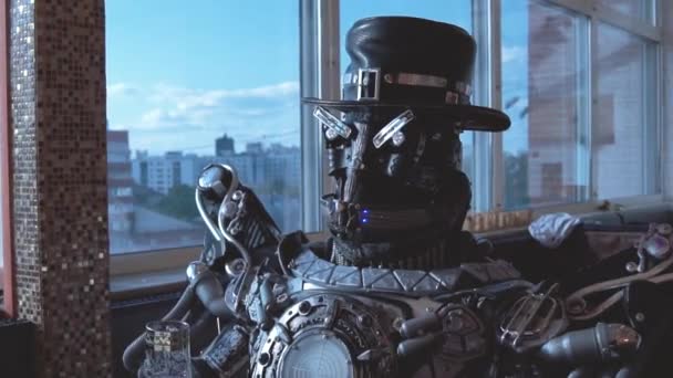 androïde en métal assis à table dans un restaurant avec un verre de vin sur fond de vue sur les immeubles de grande hauteur de la ville. Des images. L'homme robot se comporte comme un humain. Concept technologique 