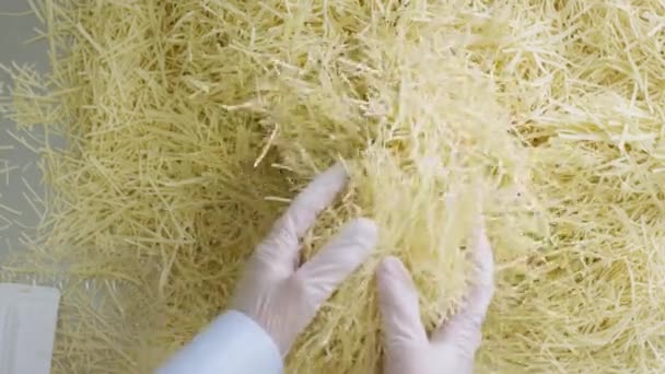 Bovenaanzicht op mannelijke handen pakken pasta of vermicelli in plastic dozen in beschermende handschoenen. Scène. Werknemer oppakken van korte pasta zakken. Werknemers verpakking rauwe macaroni in een pasta fabriek — Stockvideo