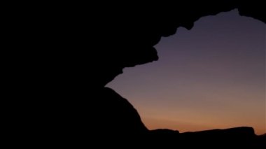 Gece gökyüzü görünümü mağara çöl. Vurdu. Şaşırtıcı kırmızı günbatımı veya bir mağara aracılığıyla yıldızlı gökyüzü. gece gökyüzü ve kayalar. Antik pencereden günbatımı.