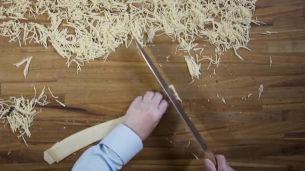 Mani vista dall'alto di chef fare tagliatelle fatte in casa uovo. Scena. Le mani del fornaio tagliano l'impasto. Vista dall'alto su mani maschili con pasta tagliente a coltello - pasta o tagliatelle — Video Stock