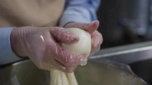 La pâte s'étire. Scène. Étendre une pâte entre deux mains dans un bol en métal avec de l'eau, fond sombre. Pâte à pétrir avec les doigts — Video