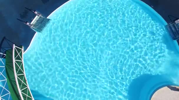 Vista superior de uma piscina de condomínio com duas cadeiras brancas vazias. Cena. Vista superior da piscina de luxo. Design exterior. Esvaziar espreguiçadeiras junto à piscina com bela piscina azul — Vídeo de Stock