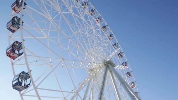 Fragmento de uma atração de roda de Ferris com táxis fechados close-up contra um fundo de céu azul, visão inferior. Cena. Roda gigante em um dia ensolarado contra um céu azul claro. Tiroteio em baixo. Parte inferior — Vídeo de Stock