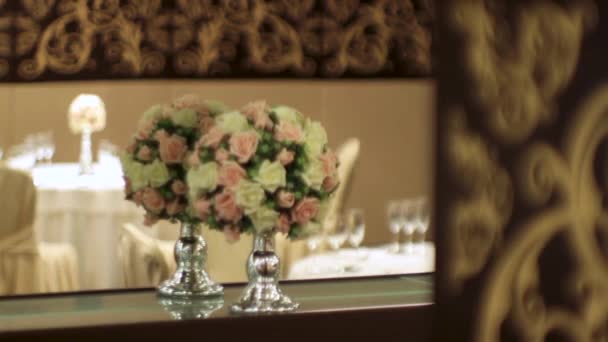 Ramo de flores artificiales en un restaurante de lujo. Escena. Decoraciones florales en la mesa en el restaurante el día de la boda. Un hermoso ramo de flores en un jarrón transparente en el fondo de la — Vídeo de stock