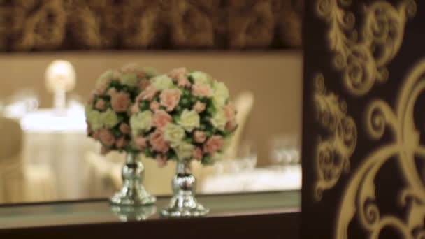 Bouquet de fleurs artificielles dans un restaurant de luxe. Scène. Décorations florales sur la table au restaurant le jour du mariage. Un beau bouquet de fleurs dans un vase transparent en arrière-plan de la — Video