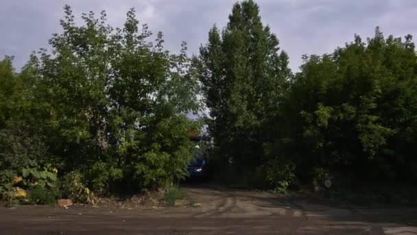 Москва, Російська Федерація - Вер, 2018: Вантажівка їде на поле дороги в лісі. Сцена. Вантажівка їде по курній дорозі серед зелені дерева в другій половині дня. Концепція перевезення — стокове відео