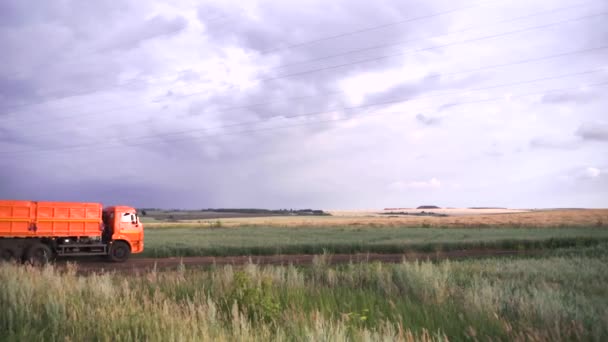 Weergave van grote capaciteit truck met lichaam reizen op landelijke weg door de velden van de boerderij. Scène. Landschap steppe en veld weg op de achtergrond van de donkere bewolkte hemel. Concept van landbouw — Stockvideo