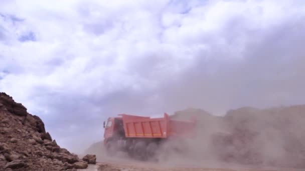 Mining truck in limestone quarry. Scene. Close up of two orange dump trucks driving from top of quarry against blue sky with clouds. Concept of career equipment — Stock Video